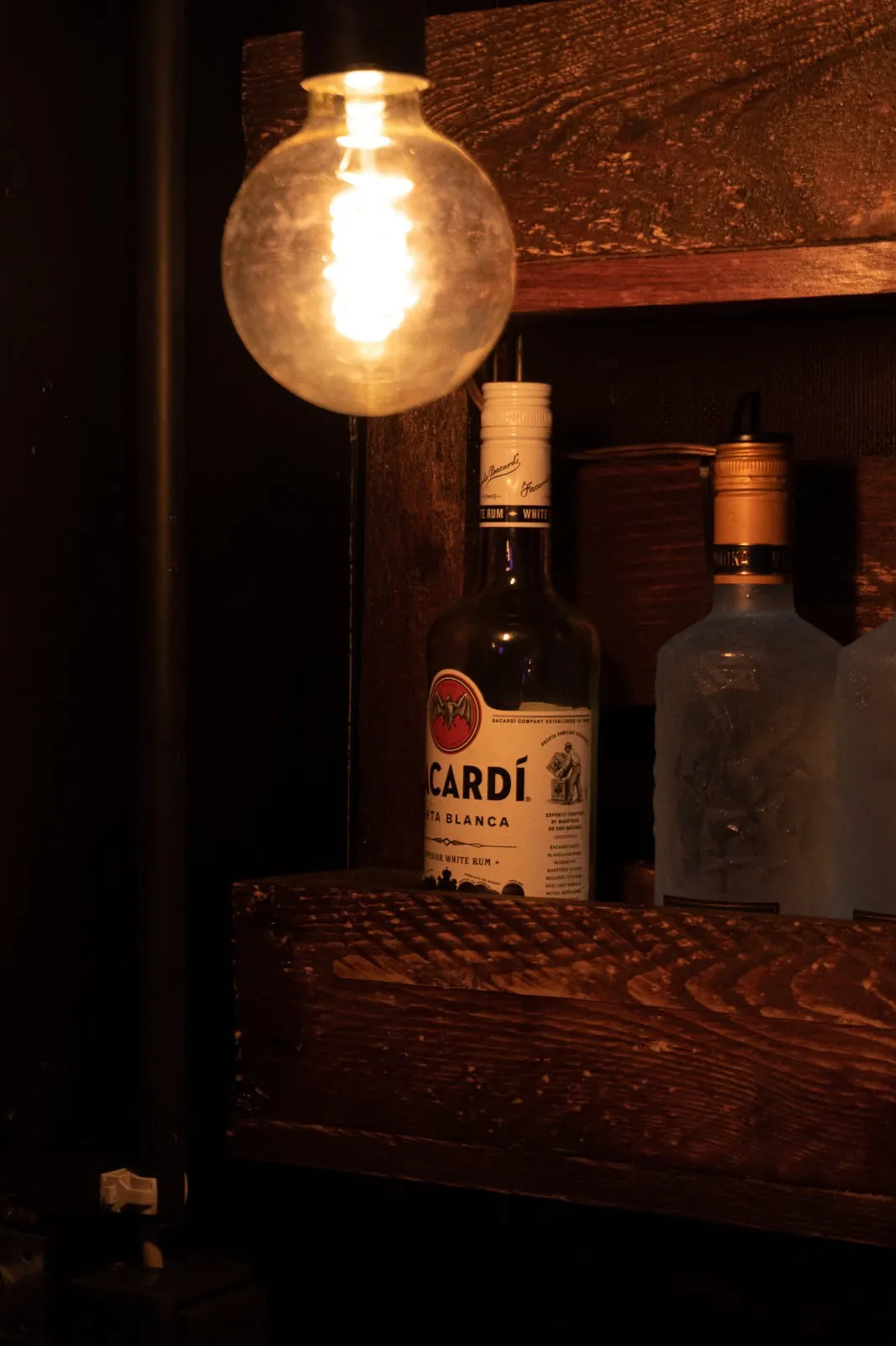 Bar-Regal mit Flaschen und Glühbirne